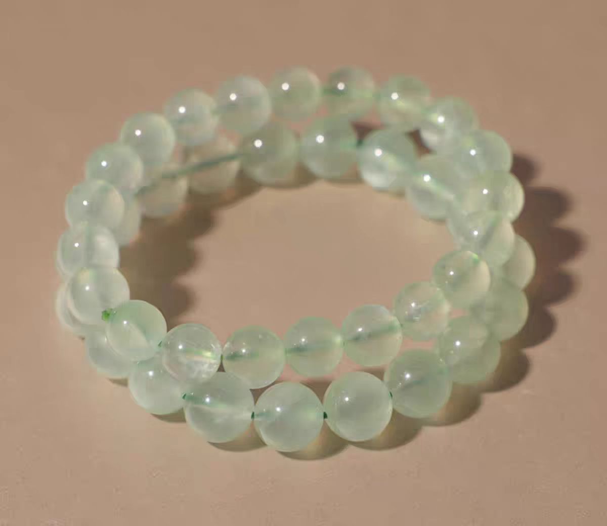 Green beaded bracelet on a beige background
