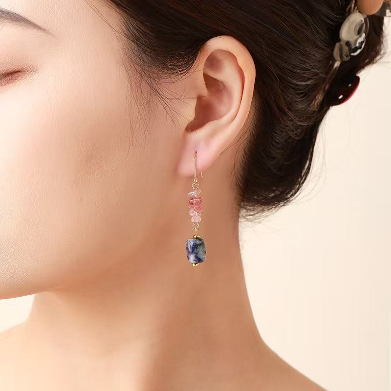 Close-up of an ear wearing a colorful earring with a neutral background