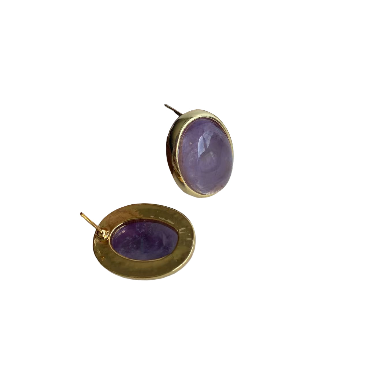 Gold earrings with purple stones on a wooden stand against a white background