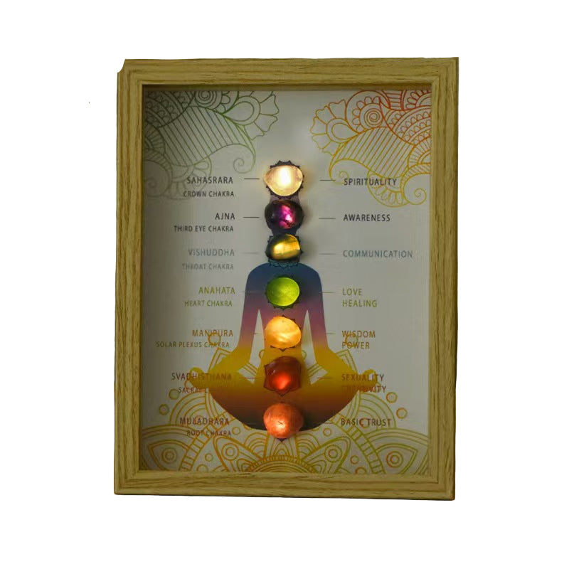 Framed artwork of a chakra diagram with colorful stones 