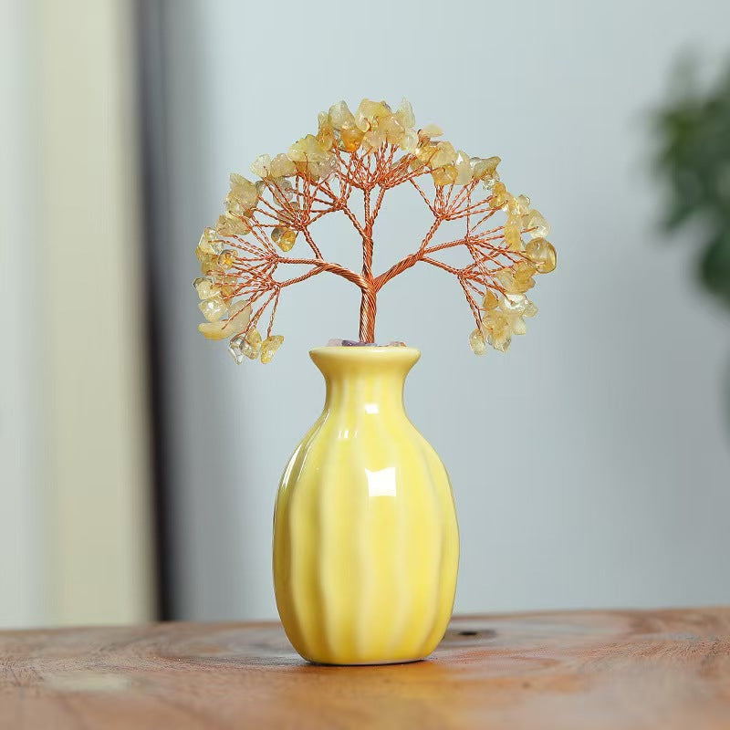 Yellow vase with decorative tree on a wooden surface