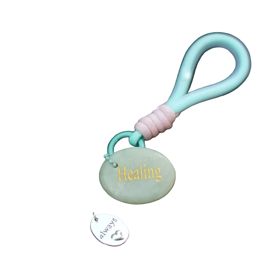 Keychain with a stone pendant labeled 'Healing' on a car window.