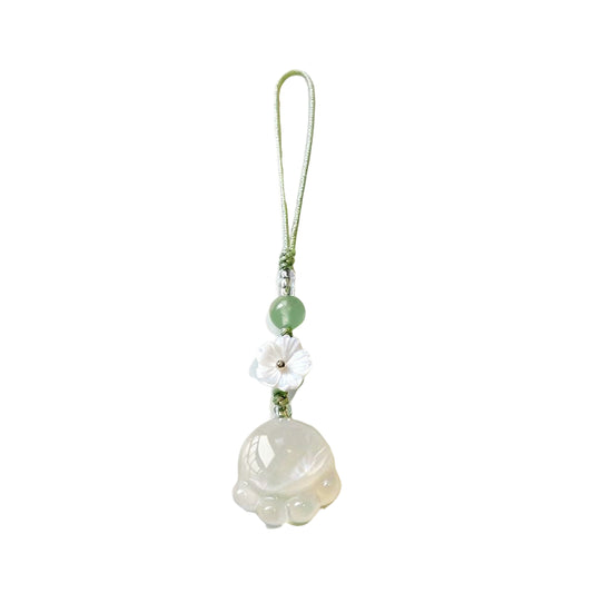 Decorative pendant with a white flower and green beads on a beige background