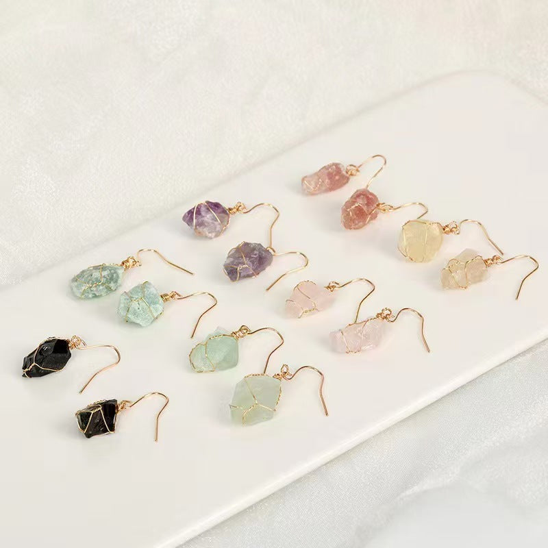 Set of colorful crystal earrings on a white surface