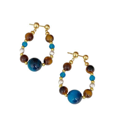 Pair of hoop earrings with blue and brown beads on a white surface