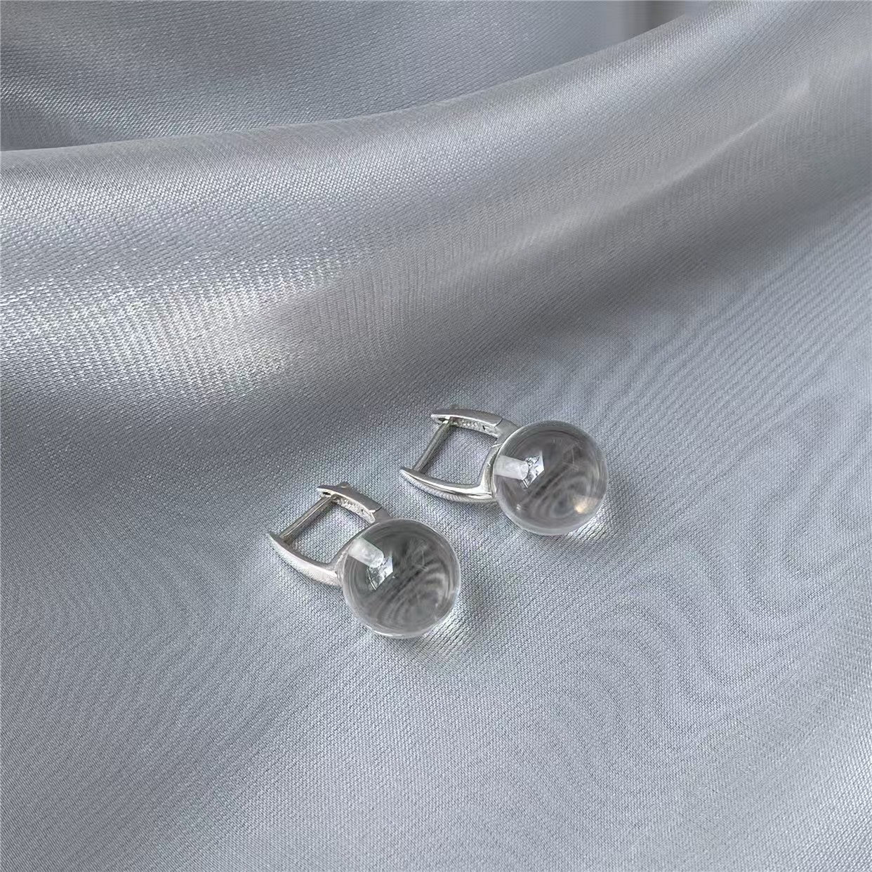Silver earrings on a light gray fabric background