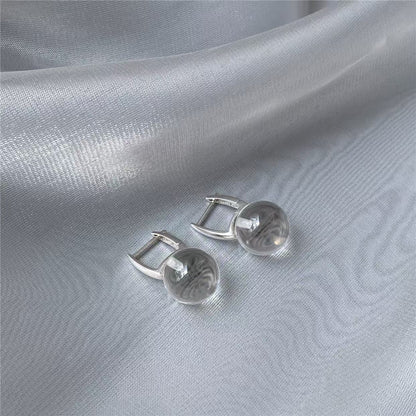 Silver earrings on a light gray fabric background