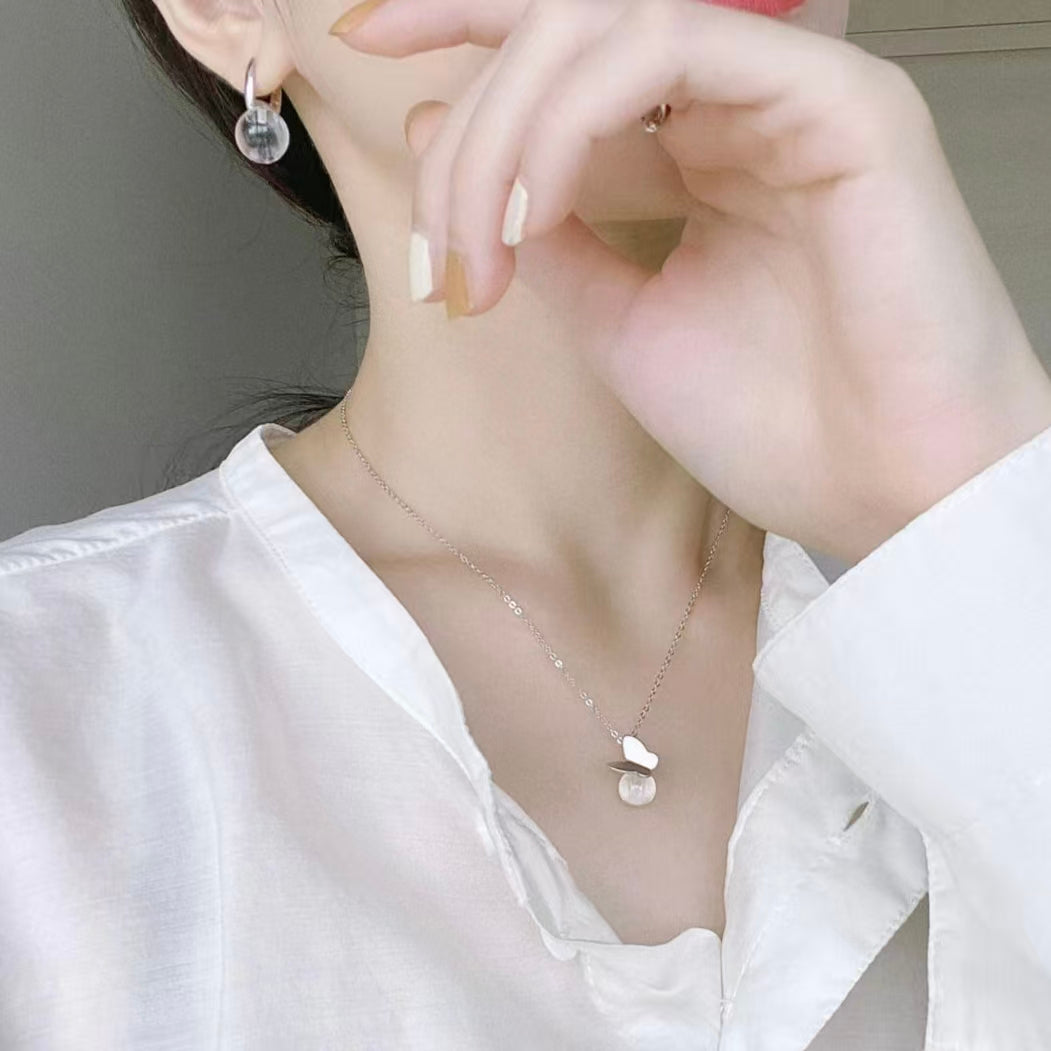 Person wearing a delicate necklace with a small pendant, close-up of neck and hand.