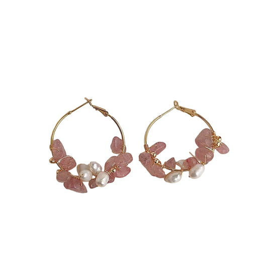Gold hoop earrings with pink stones and pearls on a white background