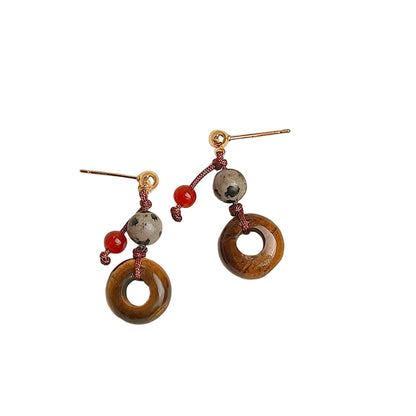 Pair of earrings with circular designs on a textured beige surface,
