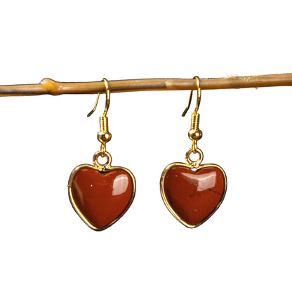Heart-shaped earrings with gold frames on a dark background