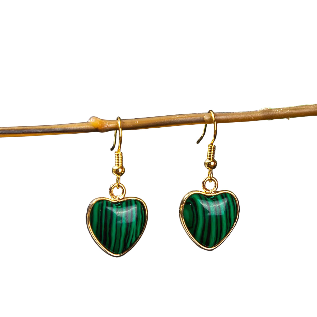 Heart-shaped green earrings with gold hooks on a dark background