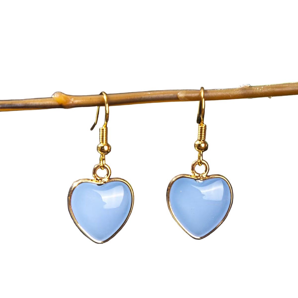 Heart-shaped blue earrings with gold hooks on a dark background