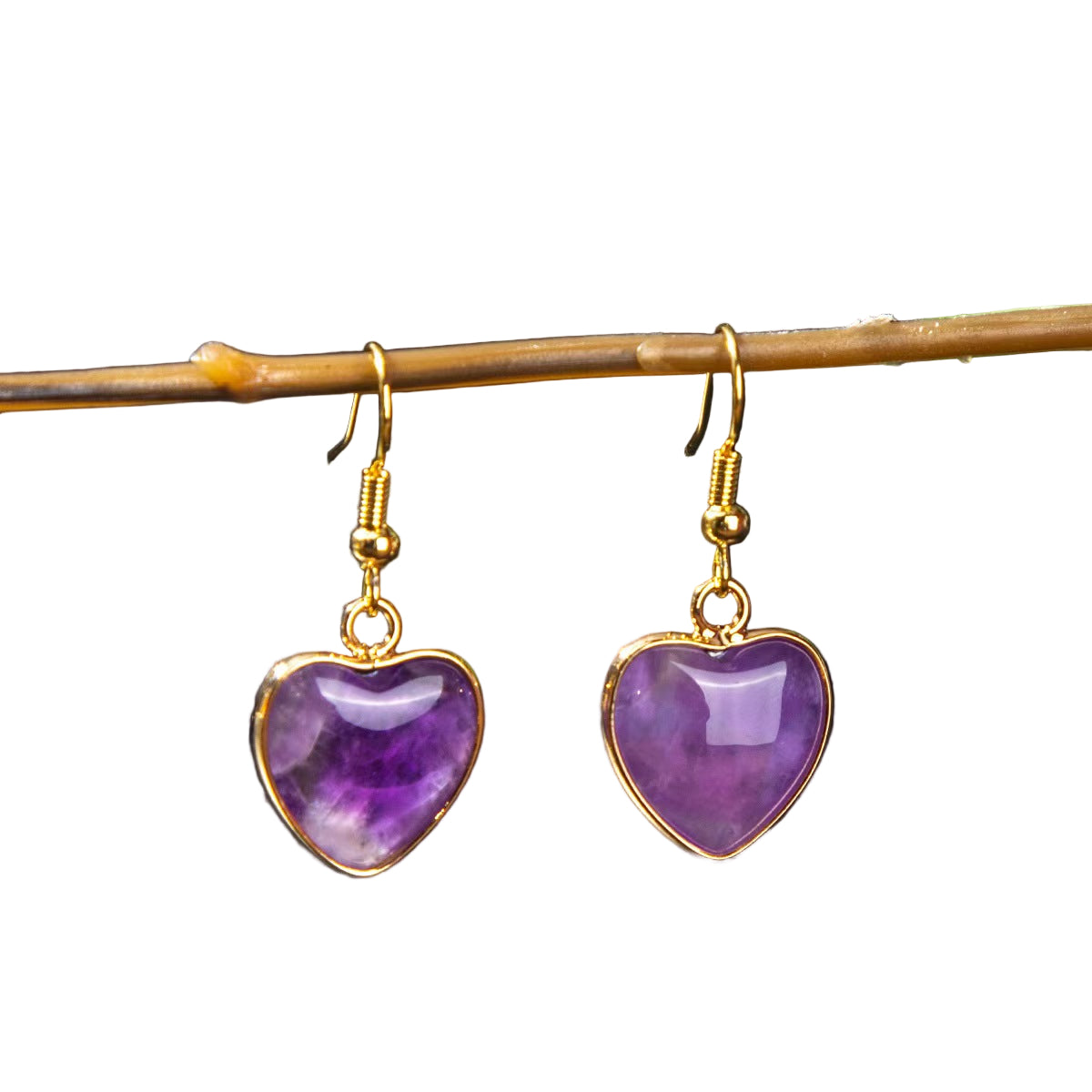 Heart-shaped purple earrings with gold accents on a dark background
