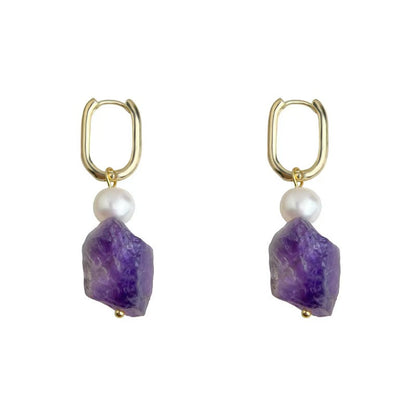Gold hoop earrings with purple stone and pearl drop on a white background
