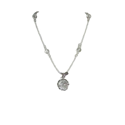 Silver necklace with a clear pendant on a white mannequin bust.
