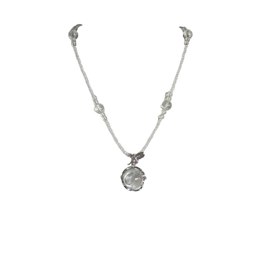 Silver necklace with a clear pendant on a white mannequin bust.