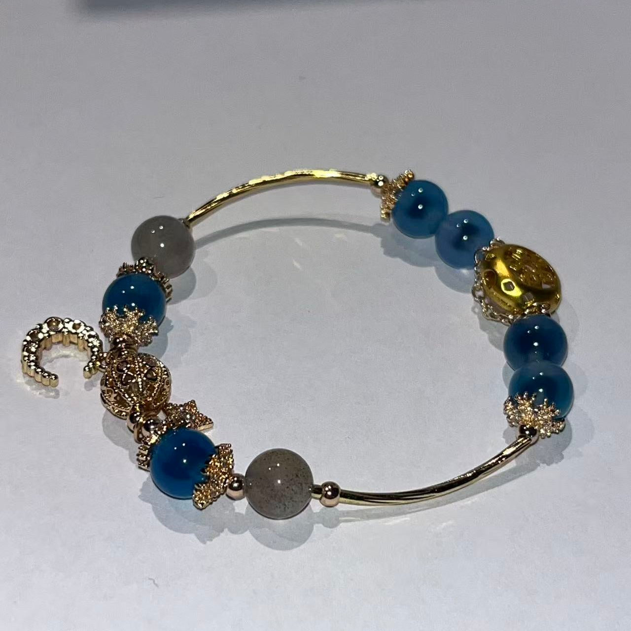 Bracelet with blue beads and gold accents on a white background