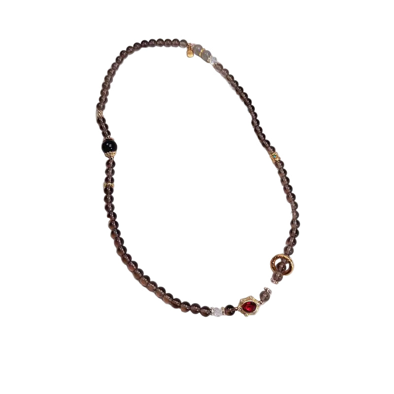 Beaded necklace with a red accent stone on a white background,