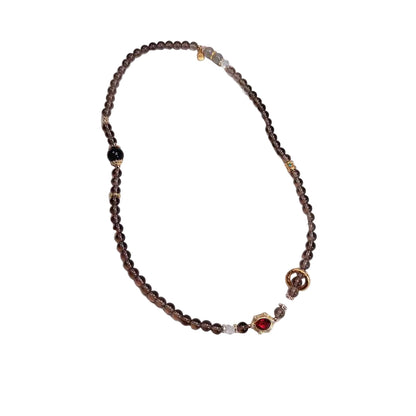 Beaded necklace with a red accent stone on a white background,