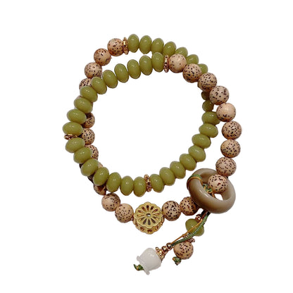 Beaded bracelet with green, brown, and white beads on a light background