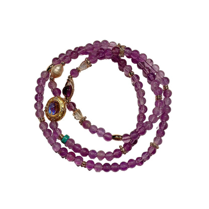 Purple beaded bracelet with gold accents on a white background