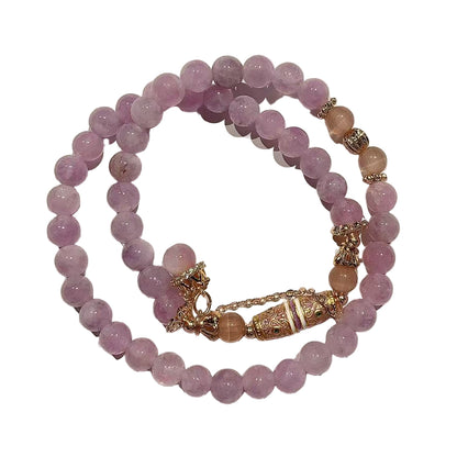 Stack of purple beaded bracelets with gold accents on a white background