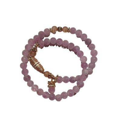 Stack of pink beaded bracelets with gold accents on a white background