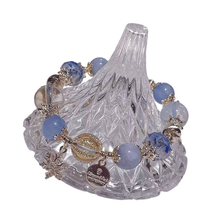 Decorative glass dish with blue beads and gold accents on a white surface.