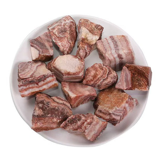 Raw meat chunks on a white plate with a white background
