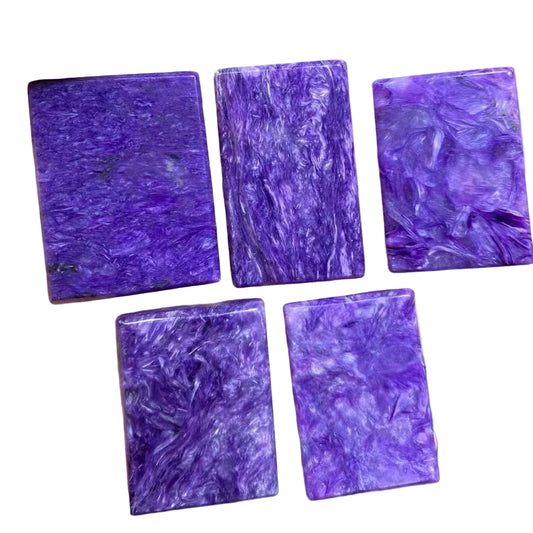 Five purple rectangular stones held in a hand against a white background