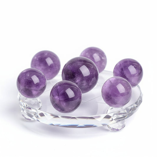 Purple crystal balls on a clear stand against a white  background