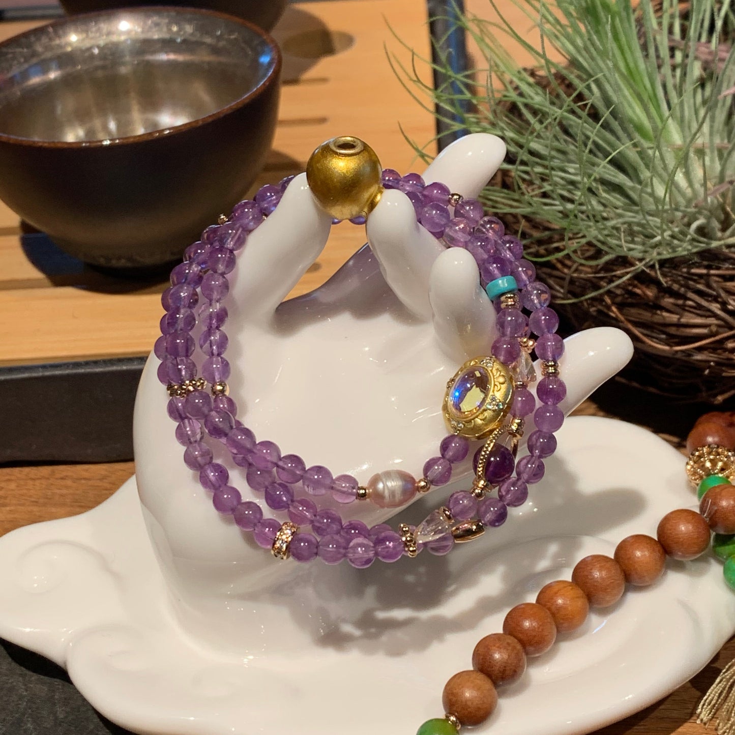 Purple beaded bracelet with gold accents on a white elephant figurine against a wooden background.