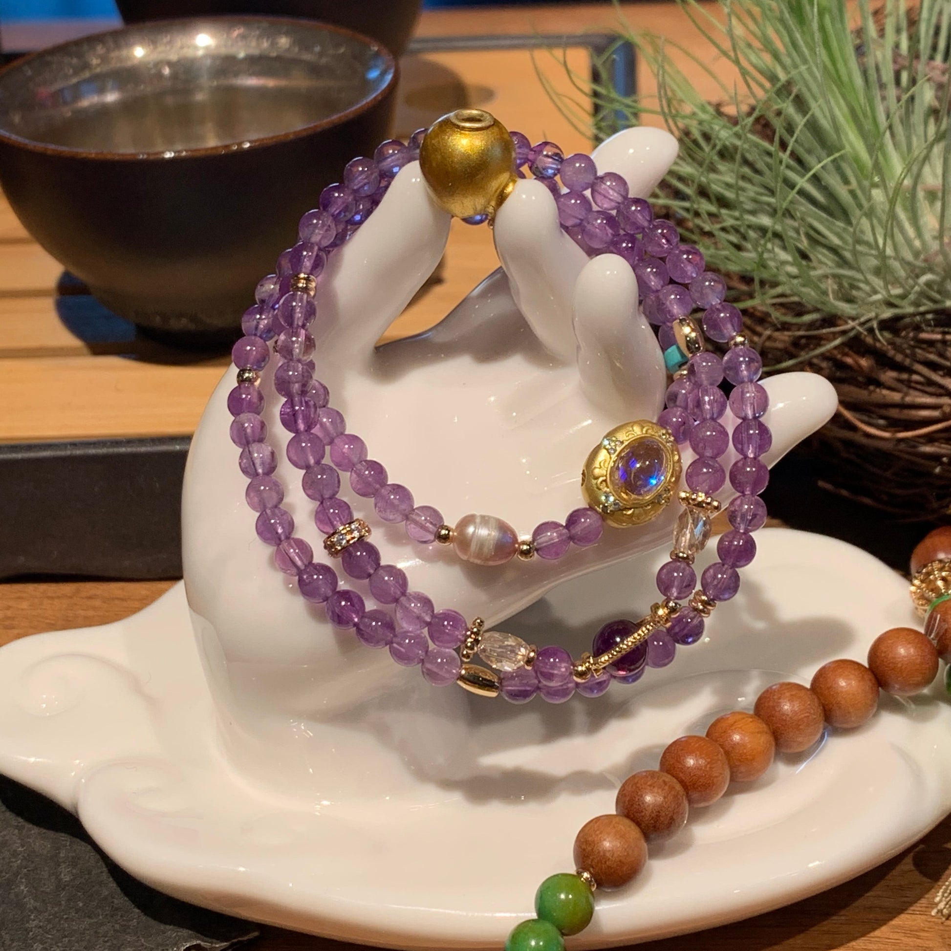 Purple beaded bracelet on a white mannequin hand with a blurred background